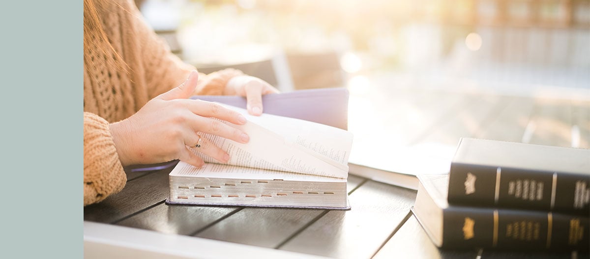 Woman reading a Bible at a table.
